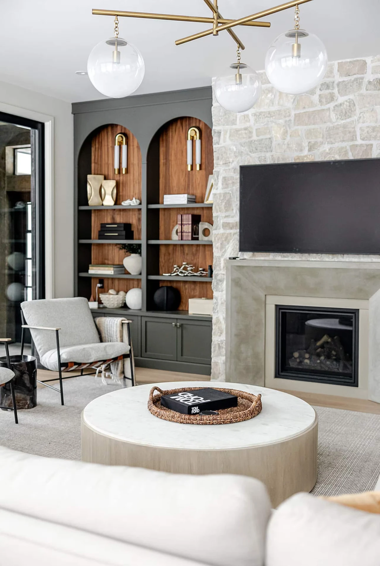 The living room with a stone fireplace and built-in shelving